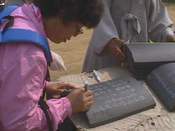 한 지역주민이 기와장에 불심을 담아 자신의 이름을 적고 있다. 